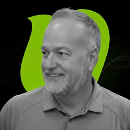 Smiling middle-aged man with gray hair and beard, wearing a polo shirt, in front of a modern green and black background.
