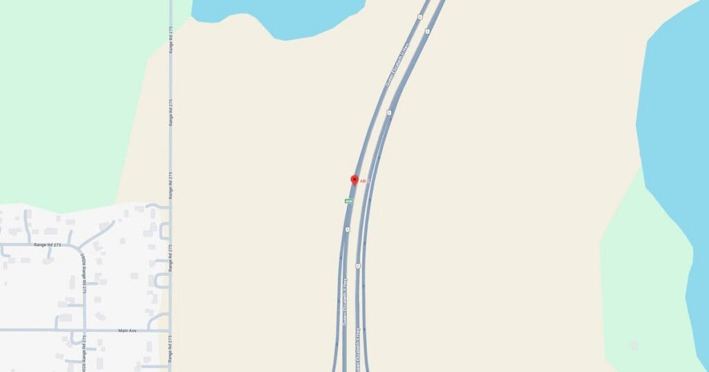 Highway running alongside a lake with surrounding trees and open land, showing a peaceful natural landscape.